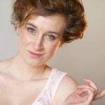 Charming portrait of a woman with styled hair, exuding elegance and grace in a studio setting.